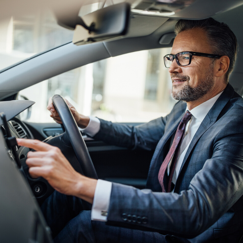 Man in suit sitting in the driver's seat of a car